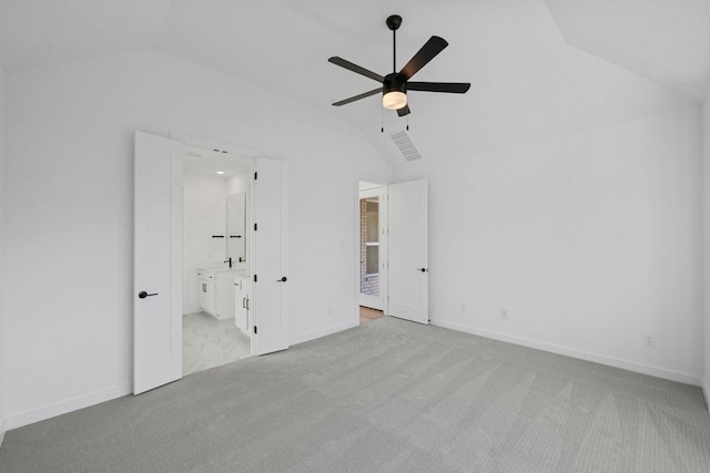 unfurnished bedroom featuring light carpet, ceiling fan, lofted ceiling, and connected bathroom