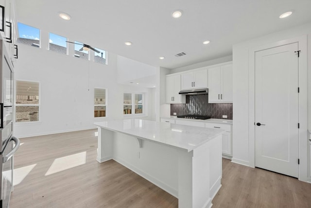 kitchen featuring black gas stovetop, a kitchen island, light hardwood / wood-style floors, and white cabinetry