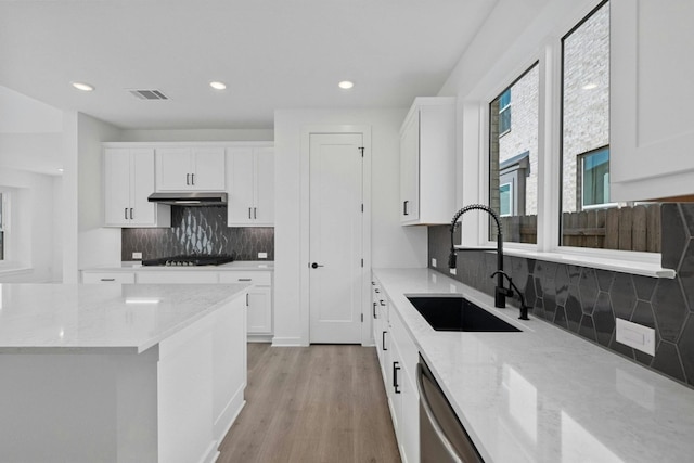 kitchen with sink, light stone counters, light wood-type flooring, and white cabinetry