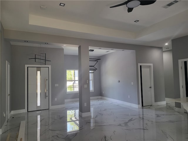 tiled entryway featuring ceiling fan and a tray ceiling