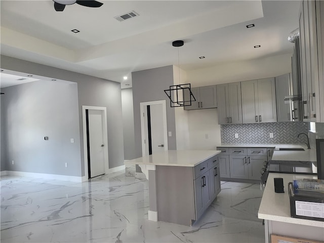 kitchen featuring backsplash, ceiling fan, a center island, light tile floors, and pendant lighting