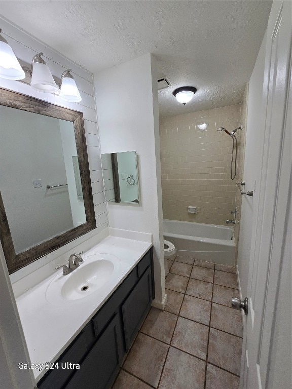 full bathroom featuring tile patterned flooring, tiled shower / bath, toilet, vanity, and a textured ceiling