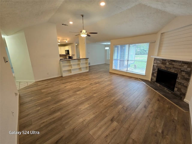 unfurnished living room with a textured ceiling, ceiling fan, dark hardwood / wood-style floors, and a fireplace