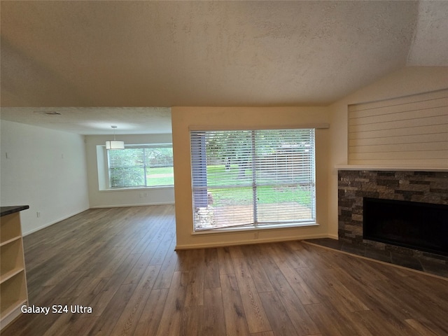 unfurnished living room with a textured ceiling, vaulted ceiling, dark hardwood / wood-style floors, and a fireplace