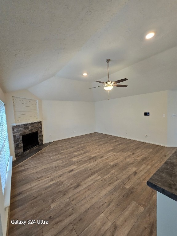 unfurnished living room featuring a fireplace, dark wood-type flooring, vaulted ceiling, and ceiling fan