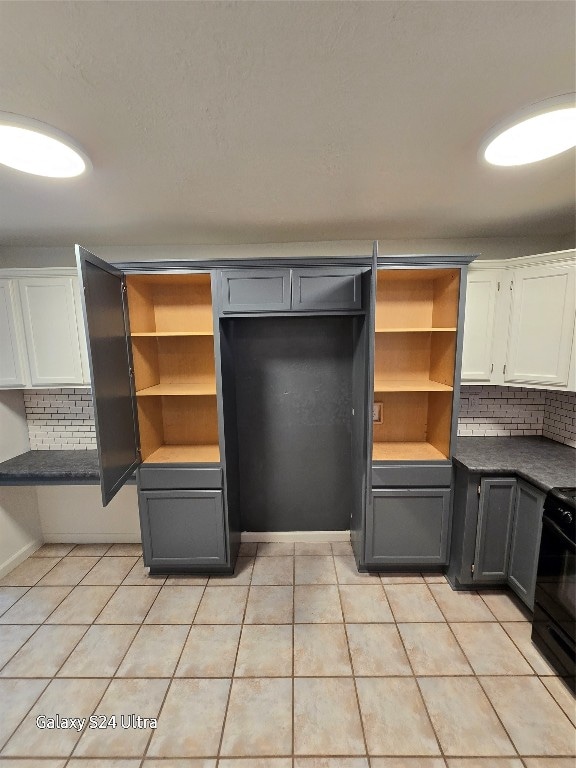 kitchen with black range oven, white cabinetry, and light tile patterned floors