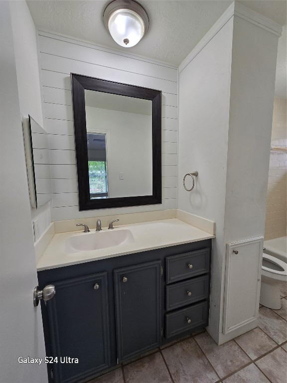 bathroom featuring toilet, tile patterned flooring, vanity, a textured ceiling, and a washtub