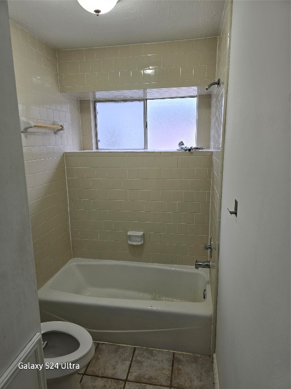 bathroom with tiled shower / bath, a textured ceiling, toilet, and tile patterned flooring