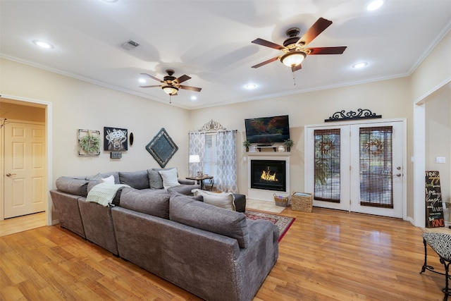 living room featuring crown molding, a healthy amount of sunlight, light wood-type flooring, and ceiling fan