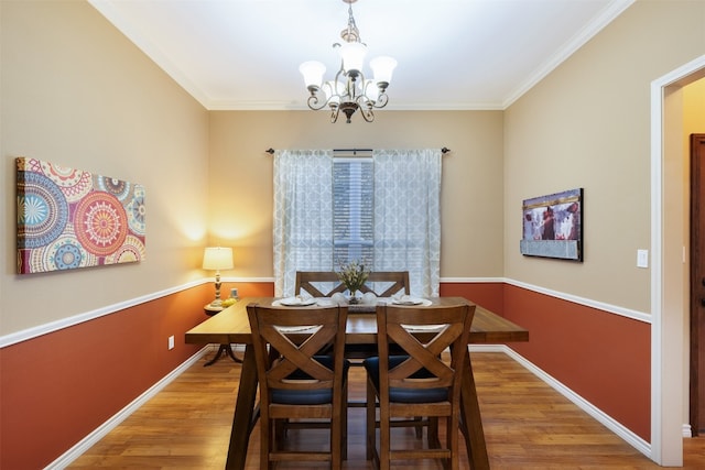 dining area featuring crown molding, hardwood / wood-style floors, and a notable chandelier