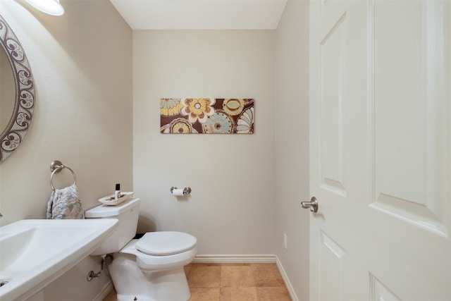 bathroom with toilet, sink, and tile patterned flooring