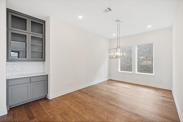 unfurnished dining area with a chandelier and hardwood / wood-style floors