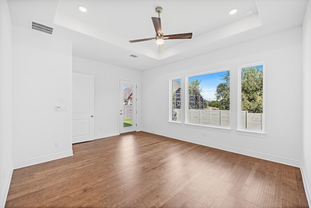 spare room featuring ceiling fan, a raised ceiling, and wood-type flooring