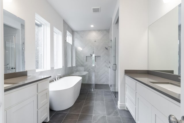 bathroom with tile patterned flooring, vanity, and plus walk in shower