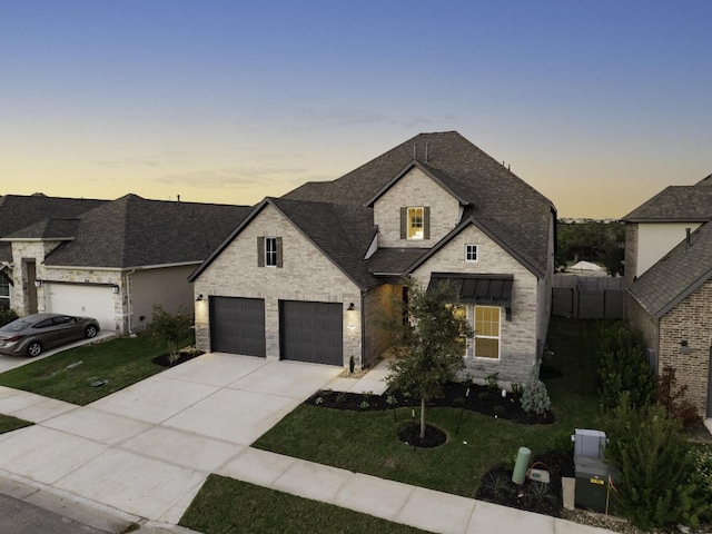 french country home with a lawn and a garage