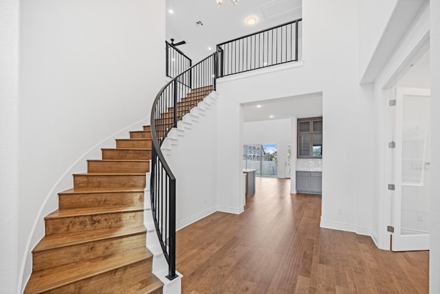 stairway featuring hardwood / wood-style floors and a towering ceiling