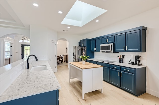 kitchen with light hardwood / wood-style floors, appliances with stainless steel finishes, sink, tasteful backsplash, and blue cabinets