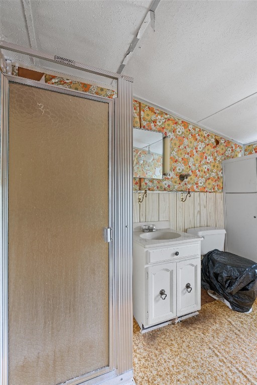 bathroom featuring walk in shower, vanity with extensive cabinet space, and a textured ceiling