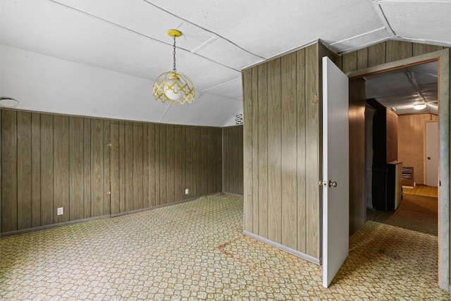 additional living space with tile flooring, lofted ceiling, and wooden walls