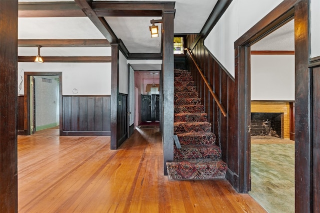 stairway featuring beamed ceiling and hardwood / wood-style floors