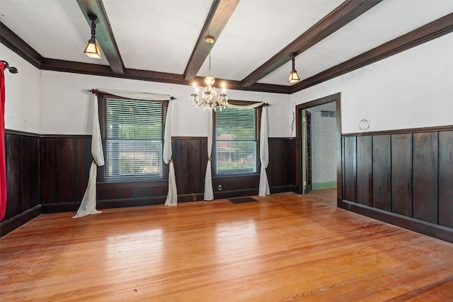 empty room with beamed ceiling, an inviting chandelier, and light hardwood / wood-style flooring