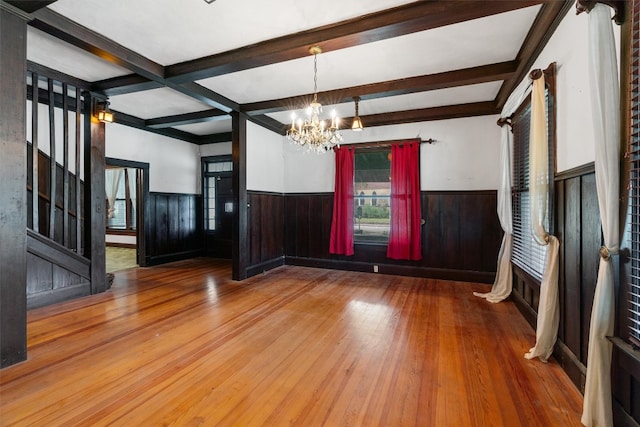 interior space with coffered ceiling, beam ceiling, an inviting chandelier, and hardwood / wood-style flooring