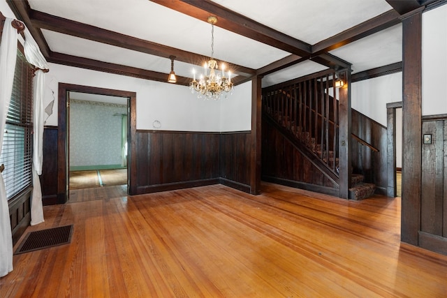 spare room with a notable chandelier, beam ceiling, and light hardwood / wood-style floors