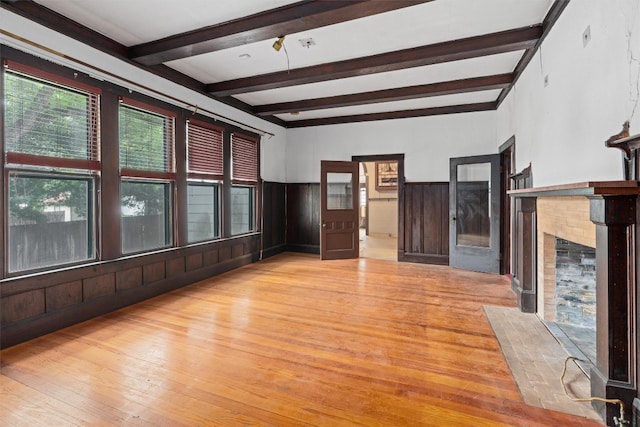 unfurnished living room featuring beam ceiling and light hardwood / wood-style floors