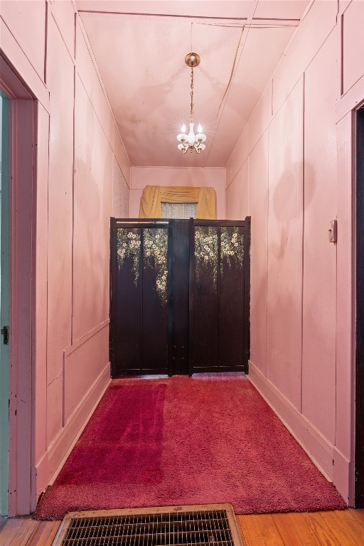 hallway featuring light hardwood / wood-style flooring and an inviting chandelier