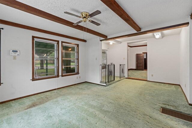 unfurnished living room featuring beamed ceiling, ceiling fan, a textured ceiling, and carpet