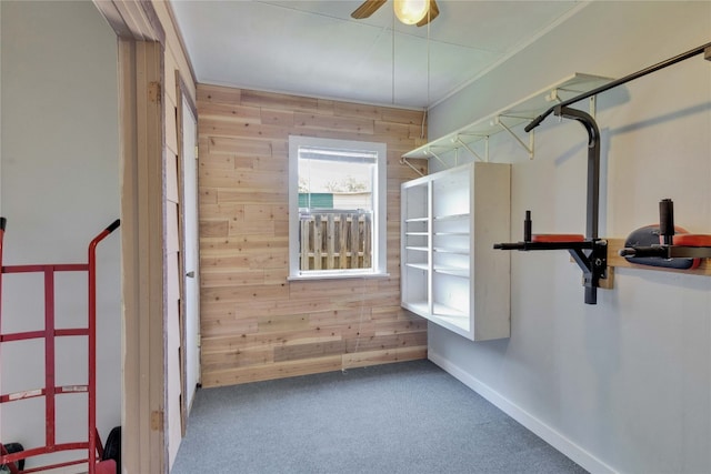 interior space featuring ceiling fan, crown molding, wood walls, and carpet