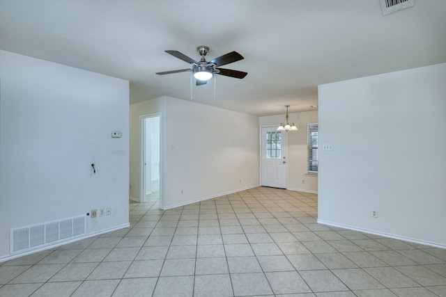 tiled spare room with ceiling fan with notable chandelier