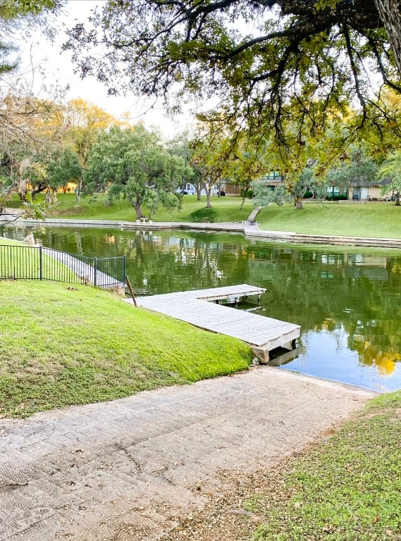 surrounding community featuring a water view, a boat dock, and a lawn