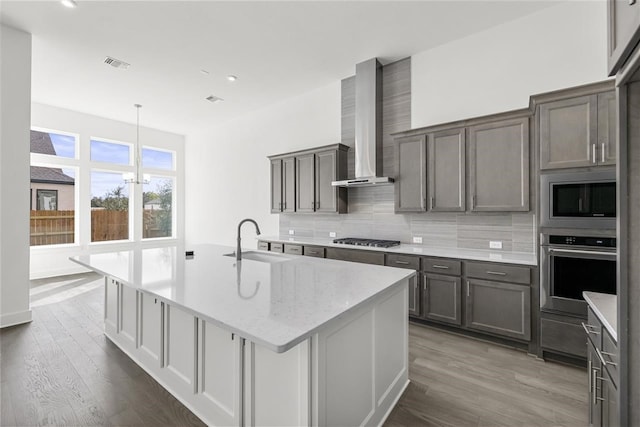 kitchen with sink, wall chimney exhaust hood, stainless steel appliances, tasteful backsplash, and dark hardwood / wood-style flooring