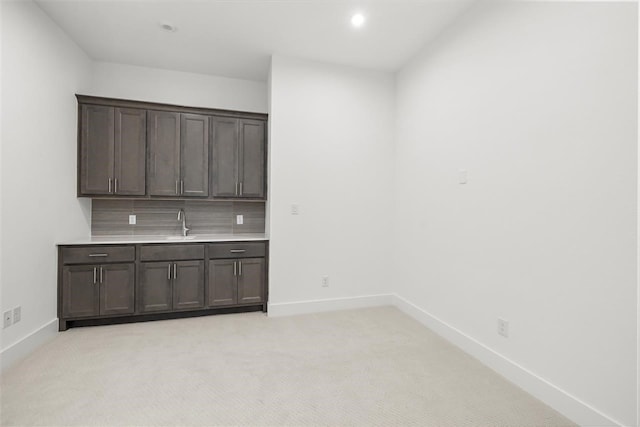 kitchen featuring light colored carpet, dark brown cabinetry, and sink