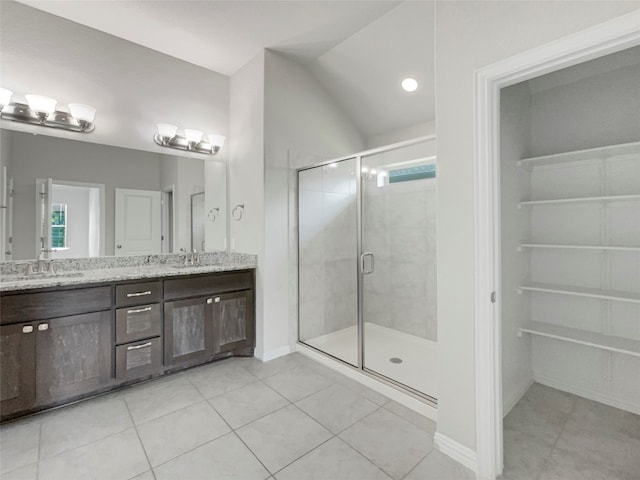 bathroom with tile floors, dual bowl vanity, vaulted ceiling, and a shower with door