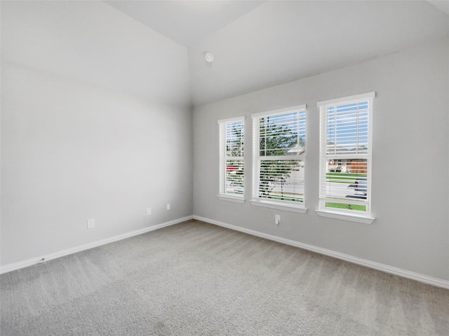 empty room featuring a healthy amount of sunlight, carpet, and vaulted ceiling