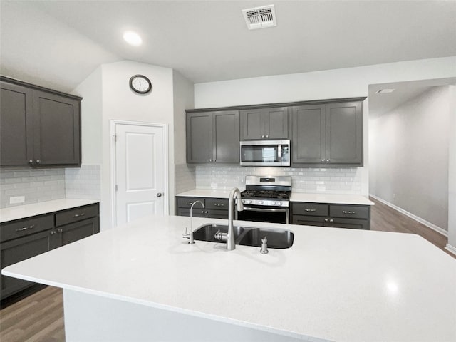 kitchen featuring a center island with sink, appliances with stainless steel finishes, dark hardwood / wood-style flooring, and sink