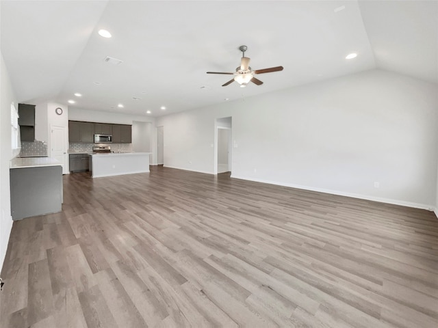 unfurnished living room with vaulted ceiling, hardwood / wood-style floors, and ceiling fan