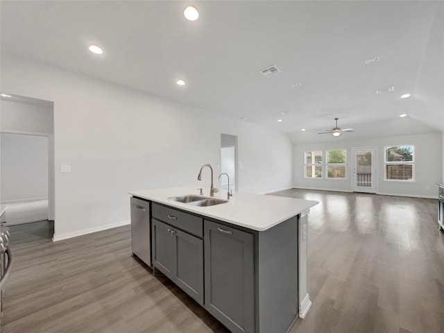 kitchen with lofted ceiling, a center island with sink, gray cabinetry, hardwood / wood-style floors, and sink