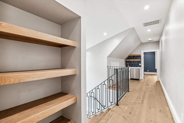 hall featuring lofted ceiling and light hardwood / wood-style floors