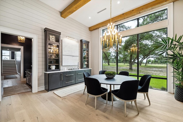 dining room featuring a wealth of natural light, an inviting chandelier, light hardwood / wood-style flooring, and beamed ceiling