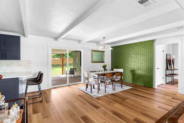 dining room featuring a notable chandelier, beam ceiling, and light wood-type flooring