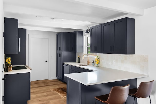 kitchen with light hardwood / wood-style flooring, kitchen peninsula, beam ceiling, tasteful backsplash, and a kitchen bar