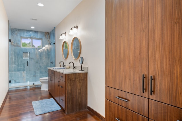 bathroom featuring a shower with shower door, wood-type flooring, vanity, and toilet