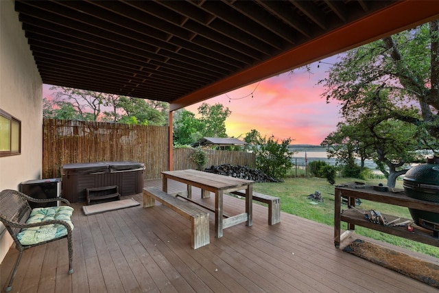 deck at dusk with a water view and a hot tub