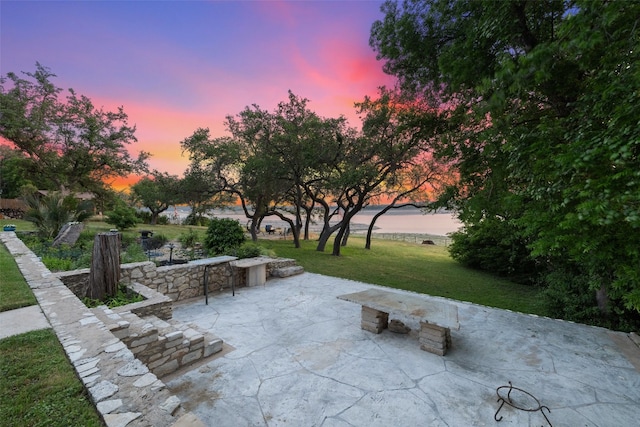 patio terrace at dusk with a yard and a water view