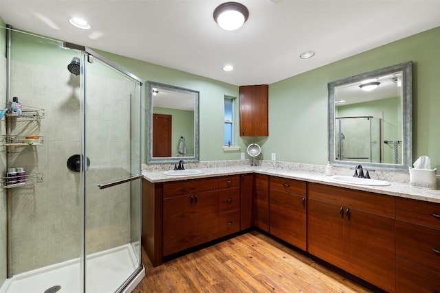 bathroom featuring a shower with door, wood-type flooring, and double sink vanity