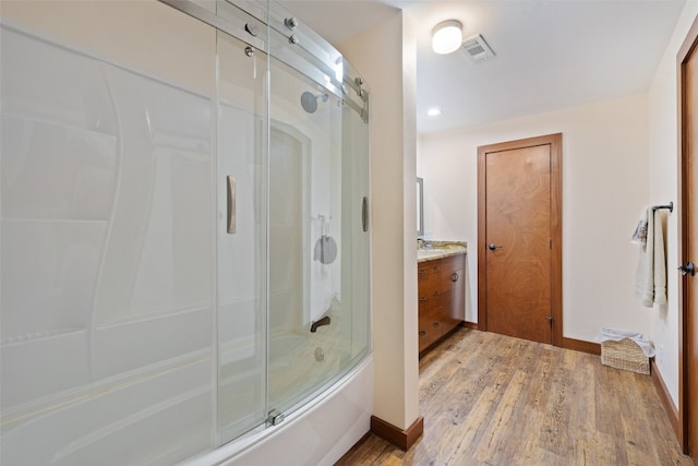 bathroom with hardwood / wood-style floors, enclosed tub / shower combo, and vanity