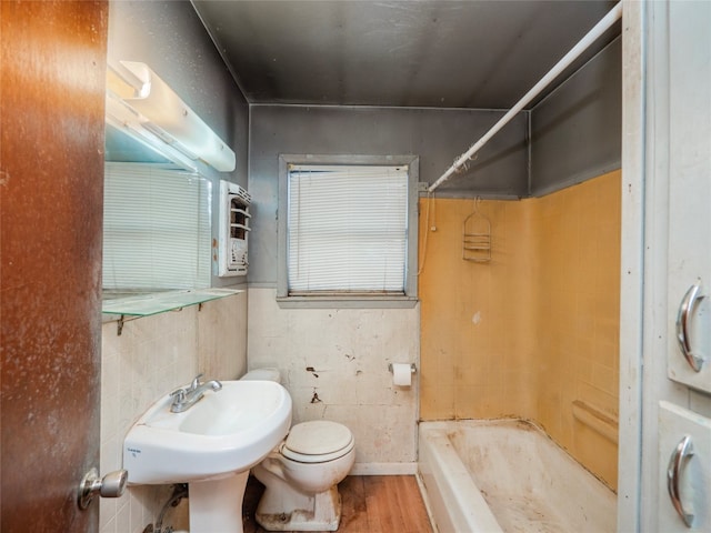 bathroom with wood-type flooring, tile walls, toilet, and  shower combination